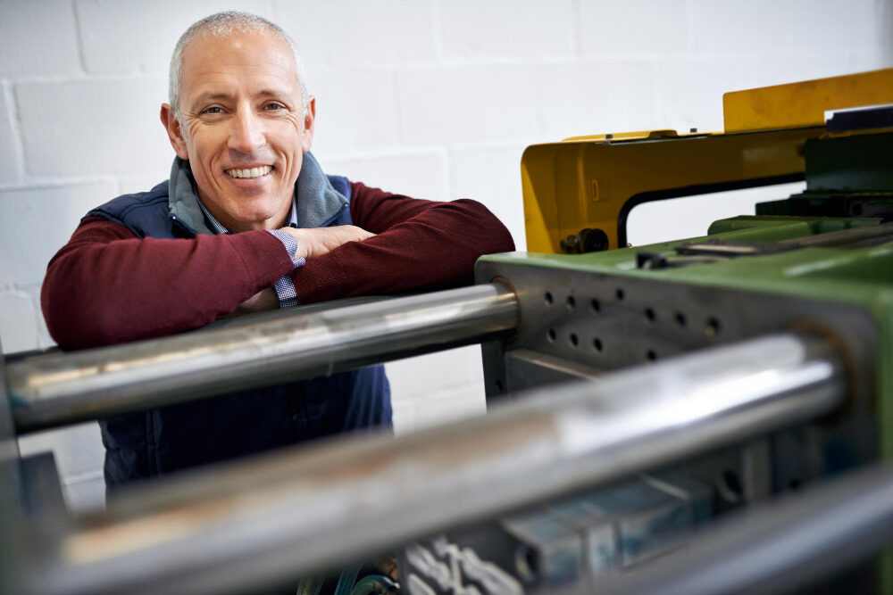 Foreman standing with hands crossed on machine in his plant
