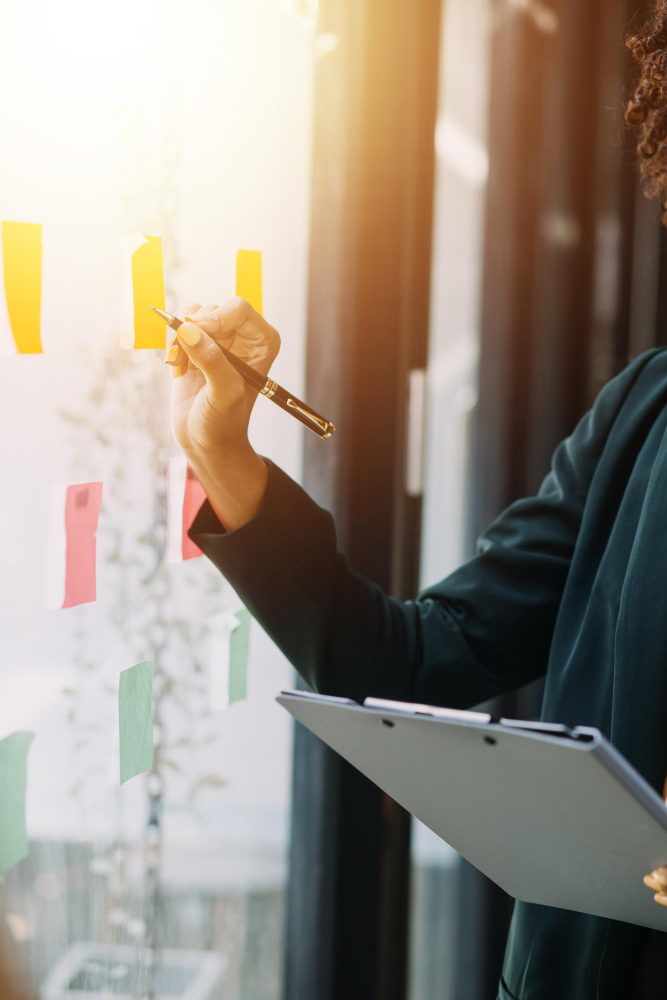 Hand of business woman writing notes on post its on a glass window